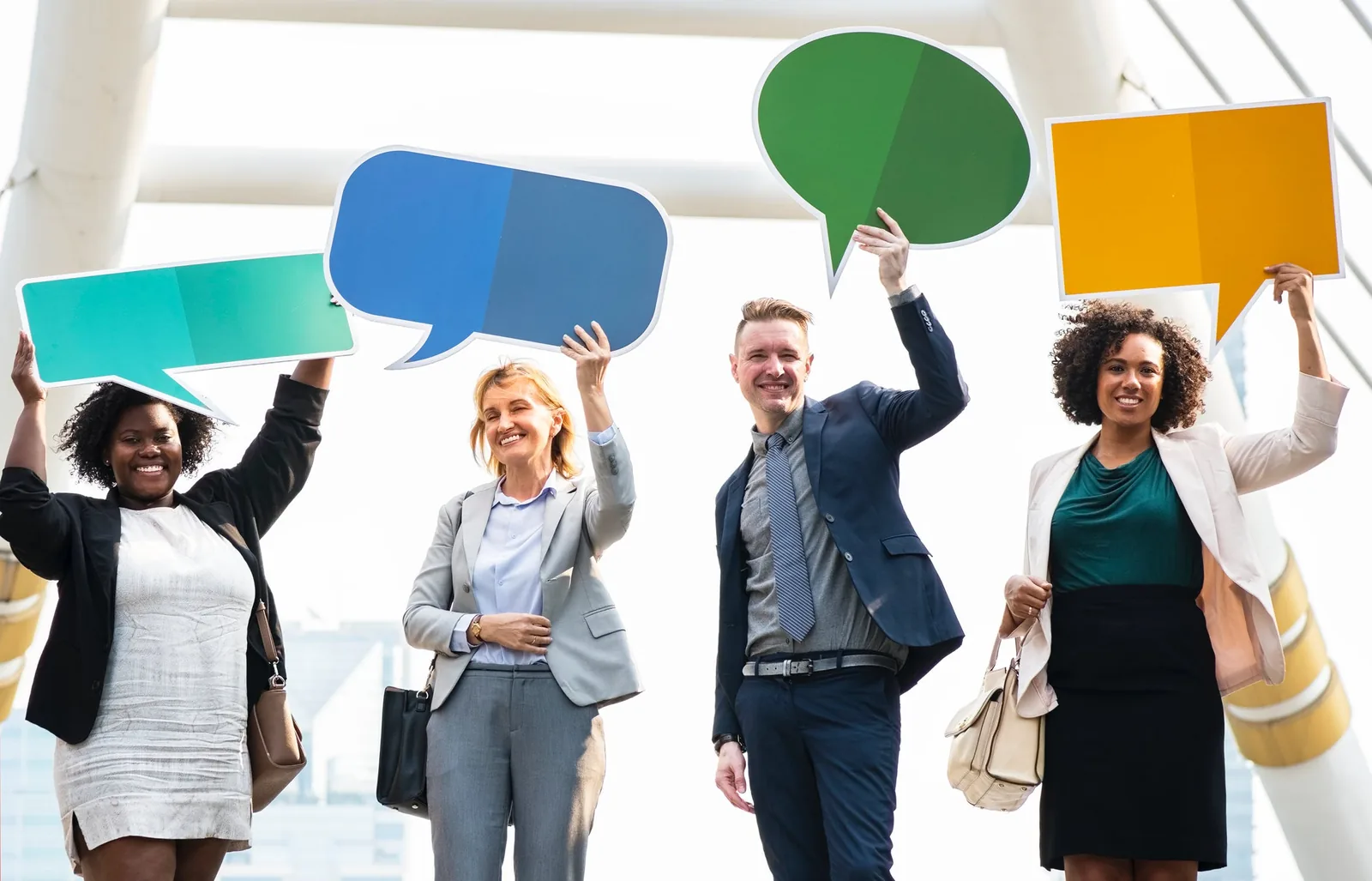 Four people holding colourful speech-bubble shapes