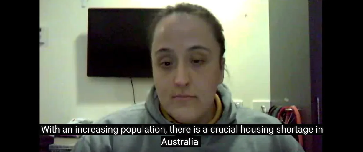 A historical video still of a person with a caption about housing shortage