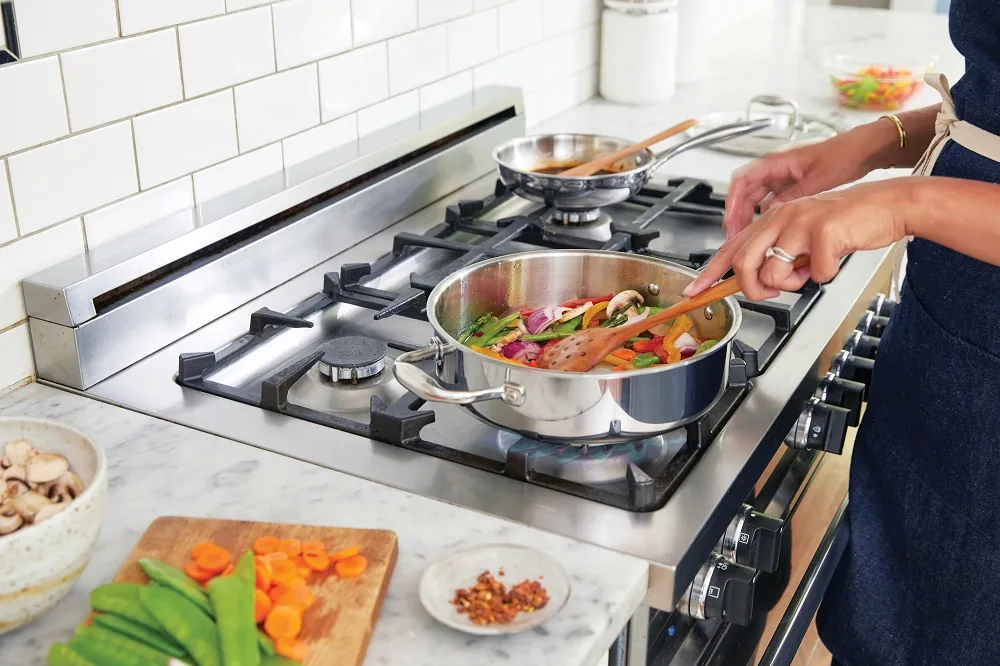 A person cooking vegetables in a pan