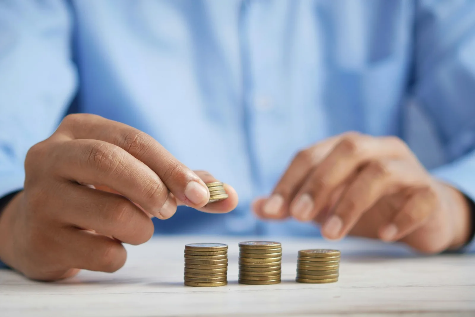 Hands arranging stacks of coins on a desk