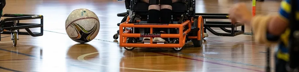 A ball beside a powerchair on an indoor sports court
