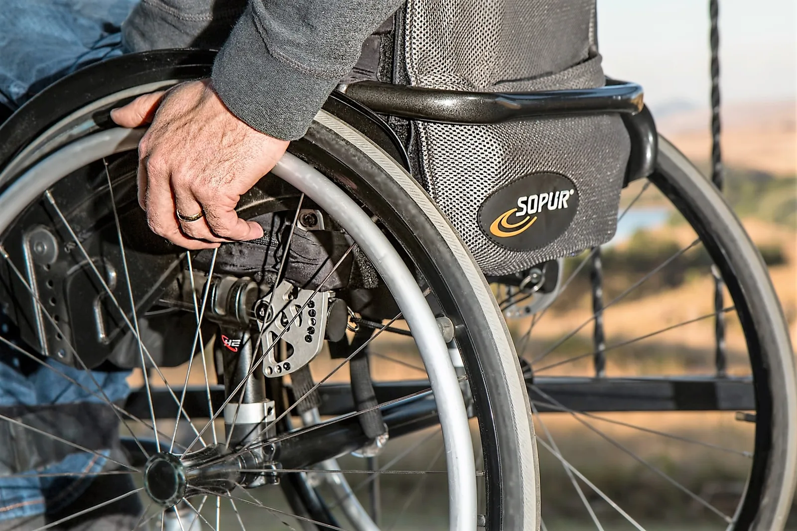 A hand resting on the rim of a manual wheelchair