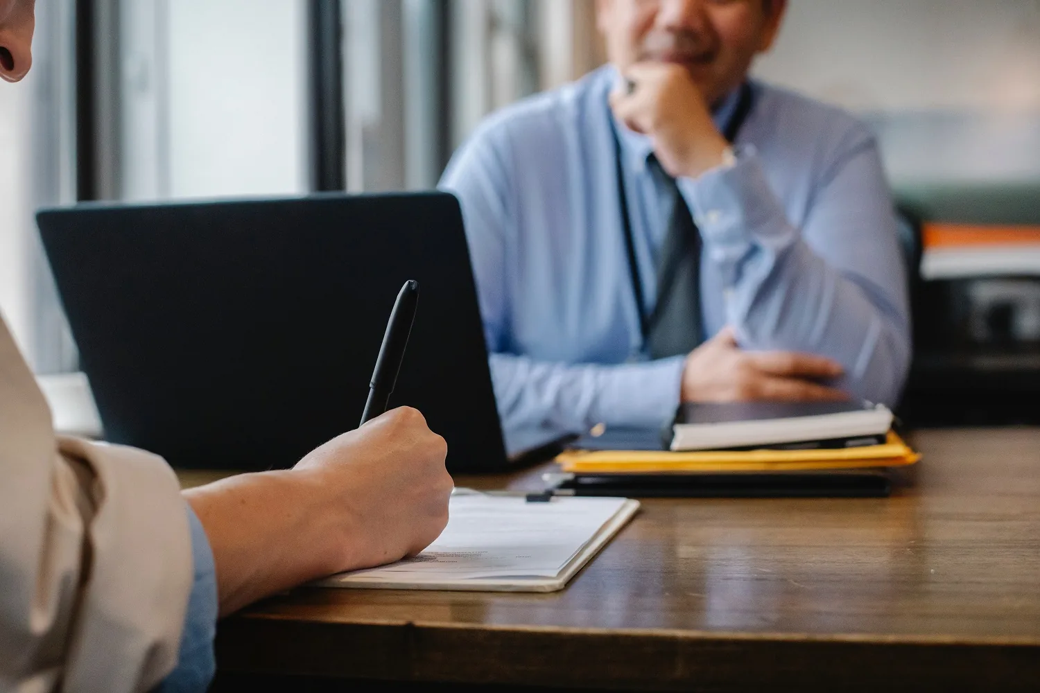 People discussing documents beside a laptop