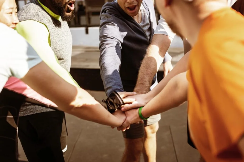 Four people in a huddle holding hands.