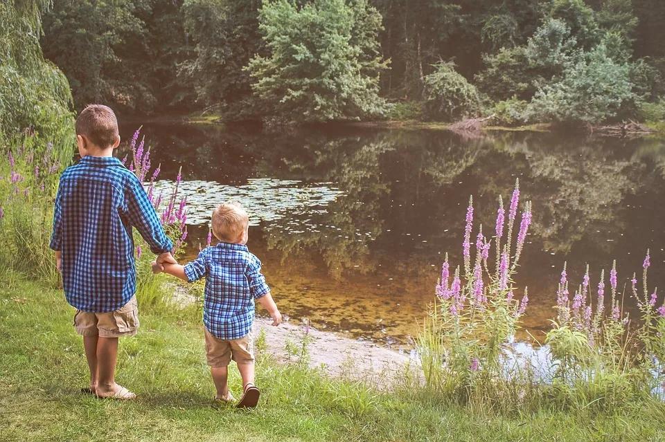 Two children walking together beside trees