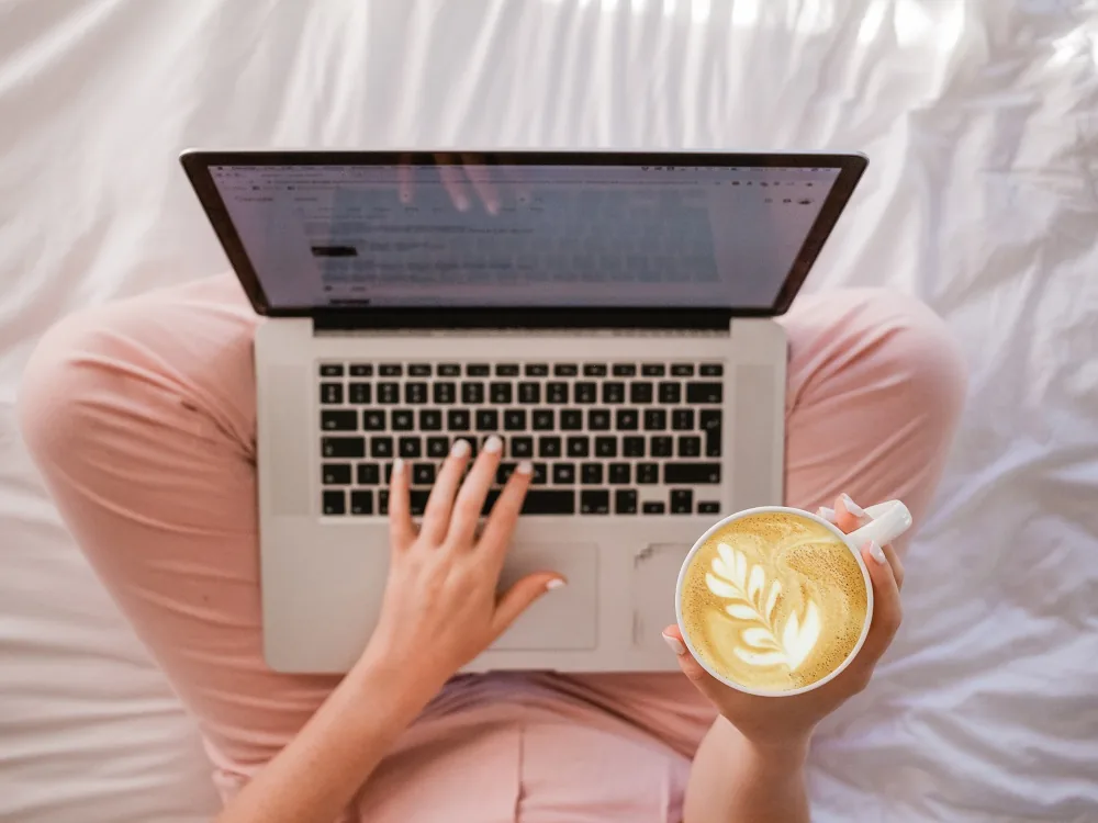 A person using a laptop while holding a cup
