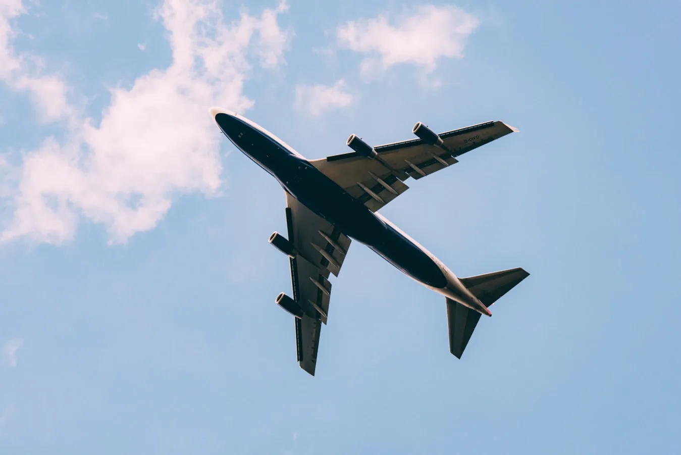 An aeroplane flying overhead against a blue sky
