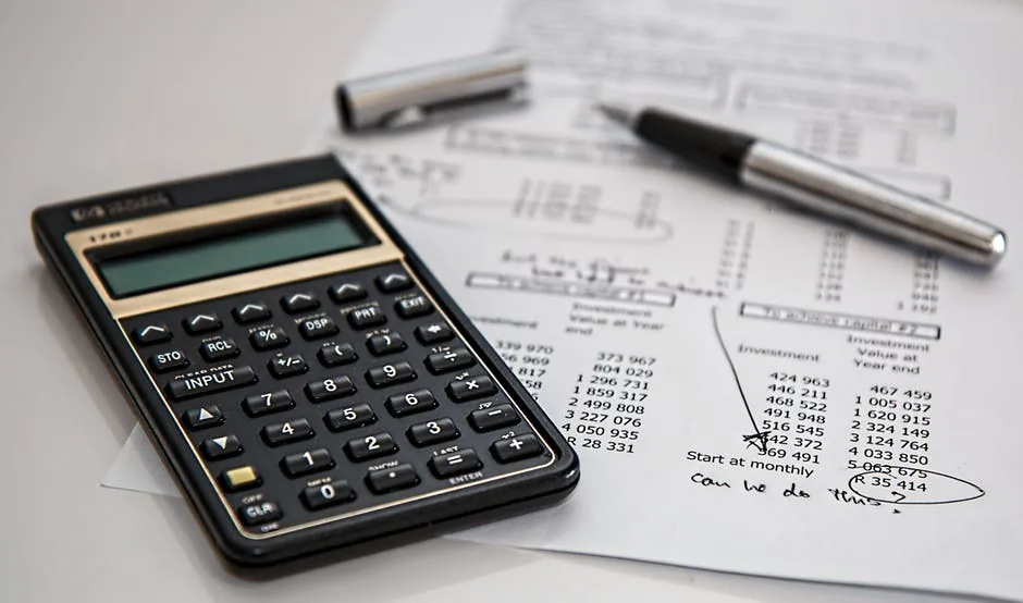 A calculator and pen on printed financial documents