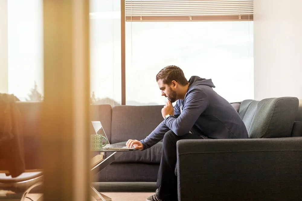 A person seated on a sofa using a laptop