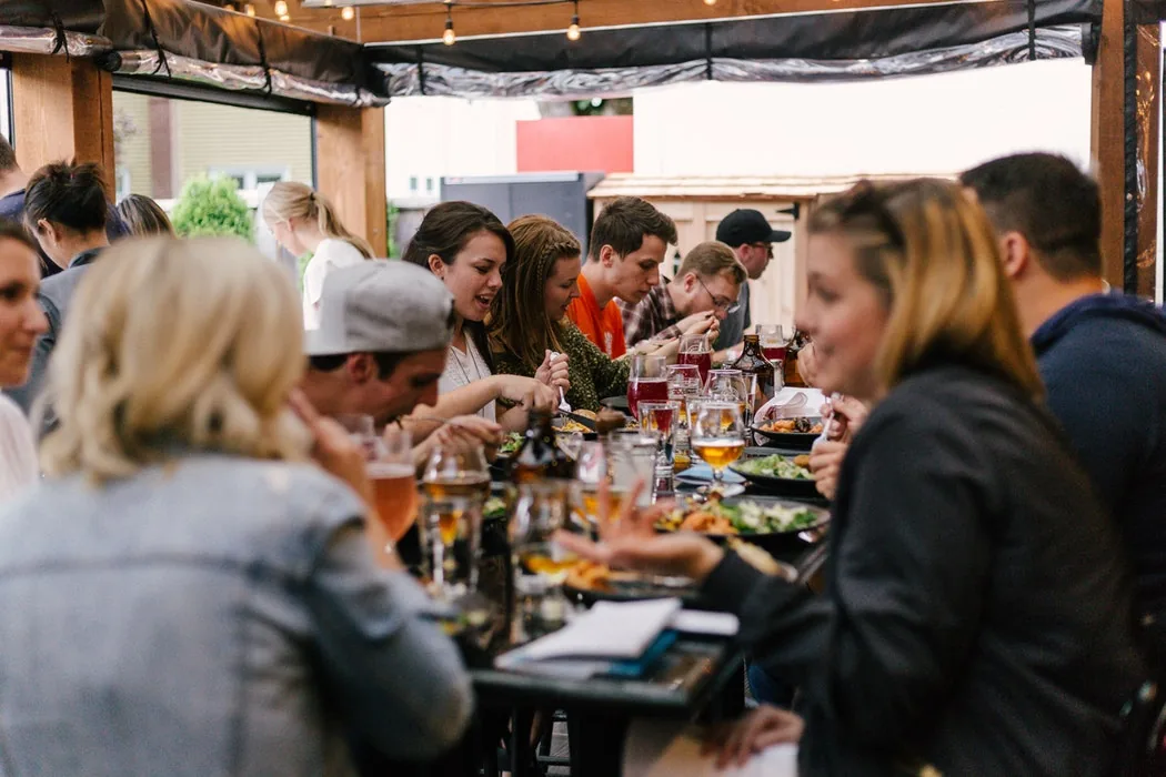A group of 20 and 30 year old people eating and drinking in a cafe.