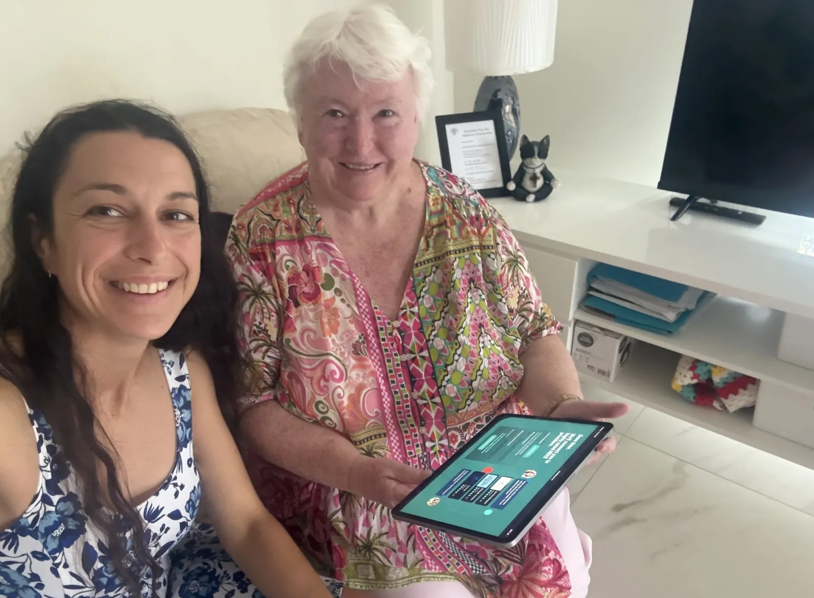 Two people smiling together while one holds a tablet