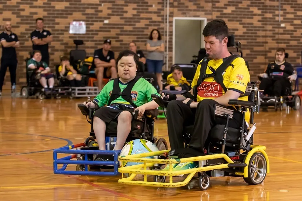 Two powerchair football players on an indoor court