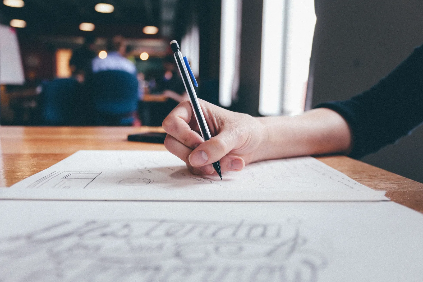 A person writing on paper at a desk