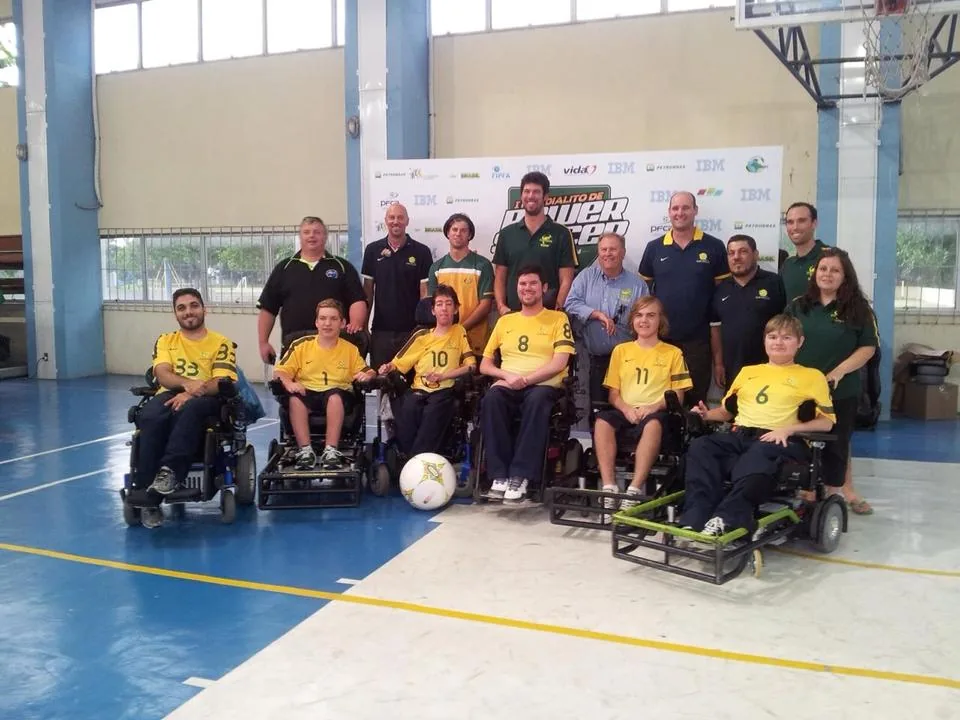 A powerchair football team with supporters on an indoor court