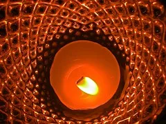 A lit candle in a patterned holder