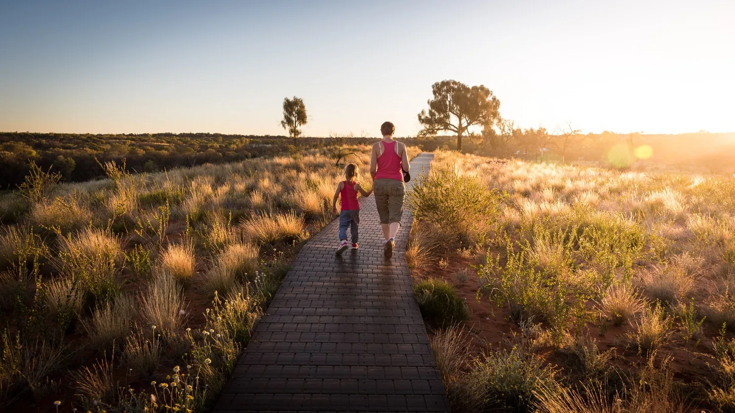 An adult and child walking along an outdoor boardwalk