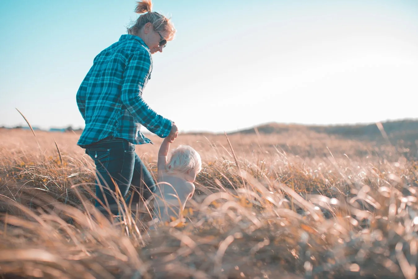 An adult and child walking together through grass