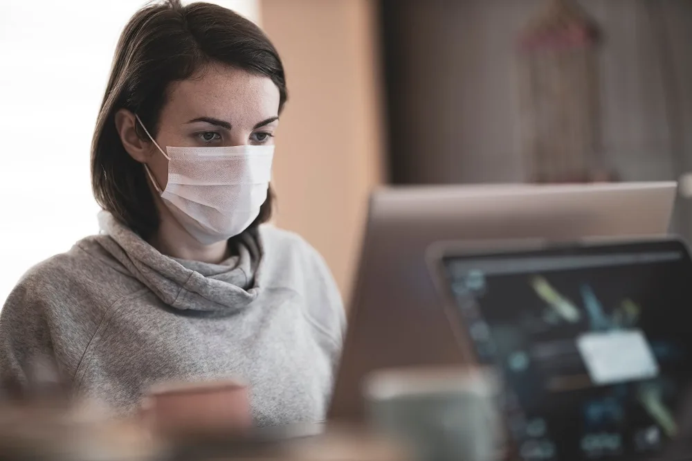 A person wearing a face mask while using a computer