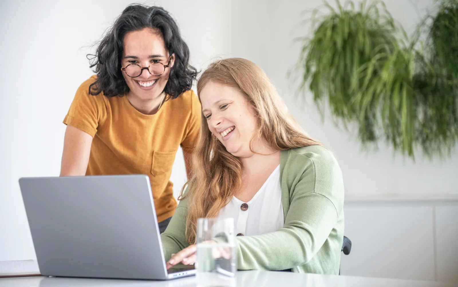 Two people discussing information beside a laptop