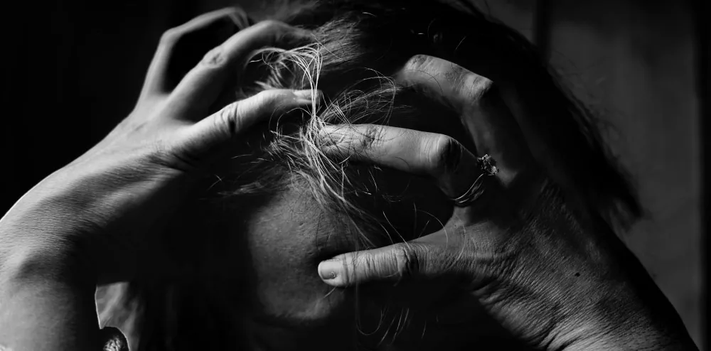 Black-and-white close-up of a person’s hands near their face