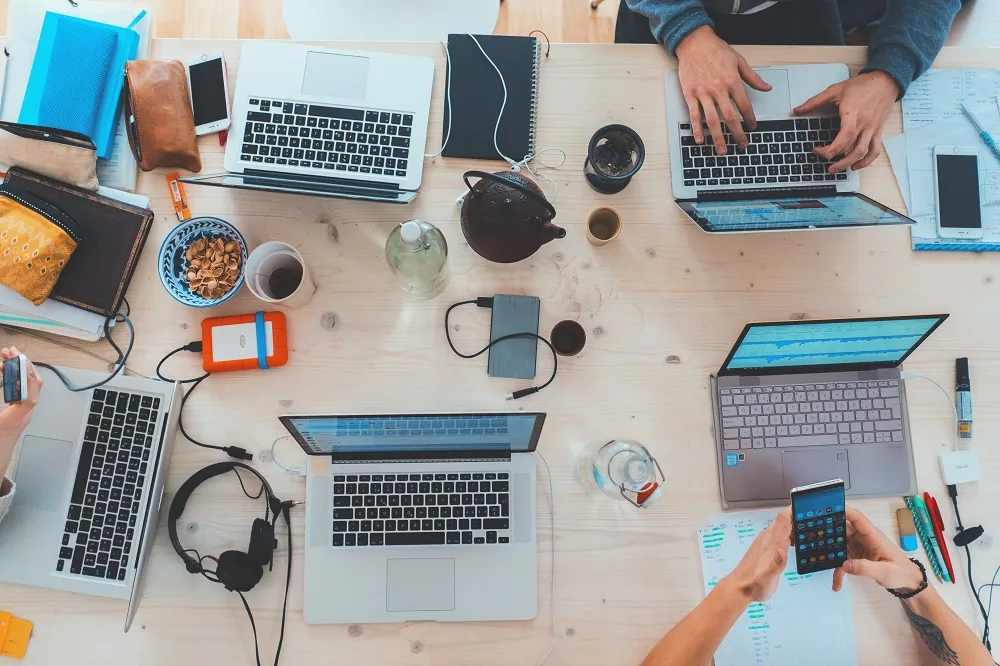 An overhead view of people working with laptops and notes at a shared table